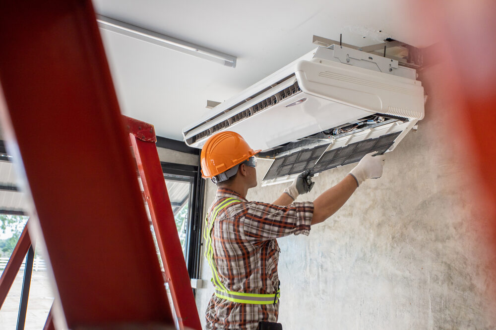 Technicien installant une climatisation, casque orange
