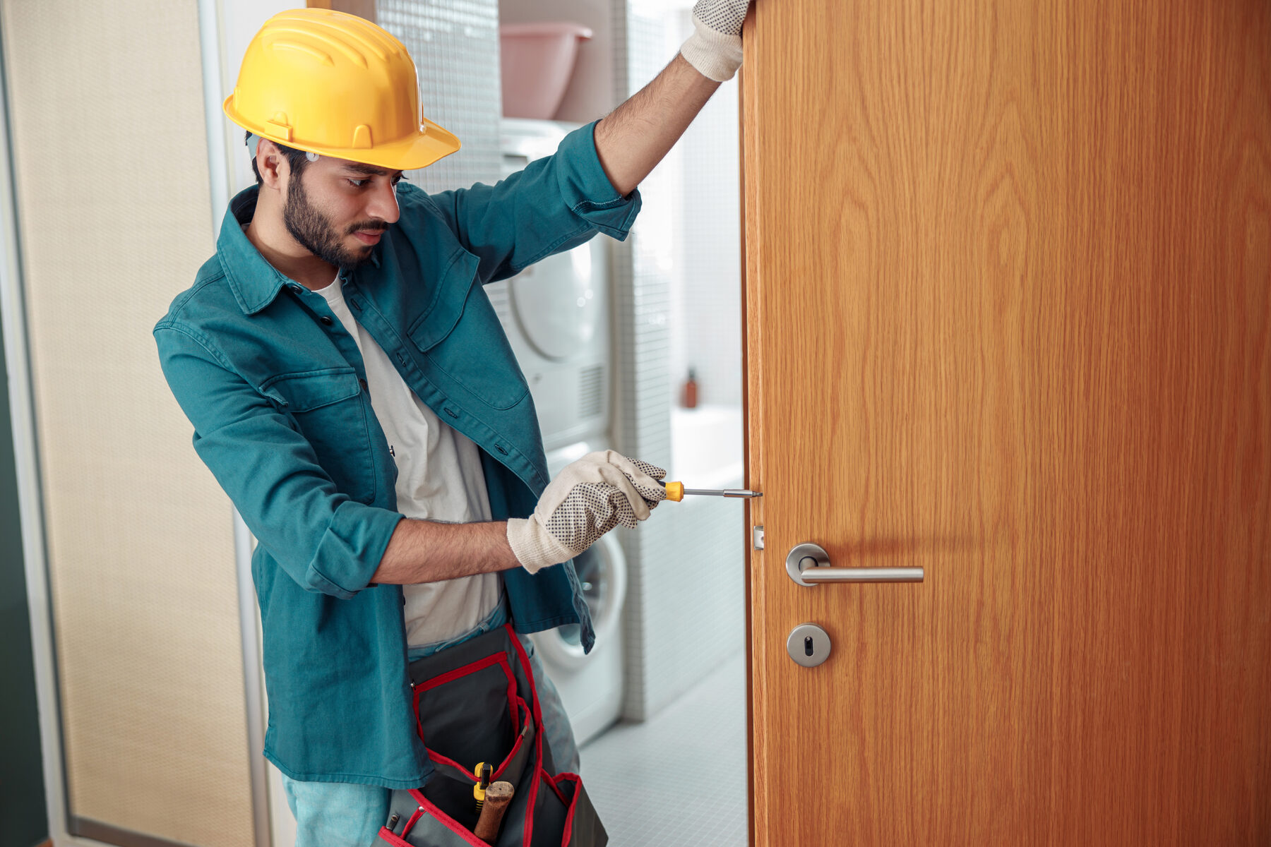 Artisan concentré, casque et ceinture à outils, au travail chez un client — le professionnel qui vous est confié